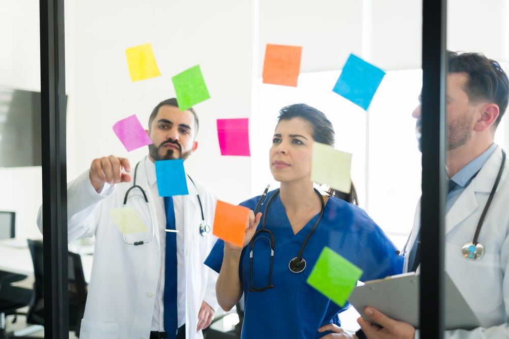 A group of people looking at sticky notes on a glass wall